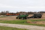 Farm equipment waiting for the final days of the 2021 harvest sit in a field as another coal empty passes